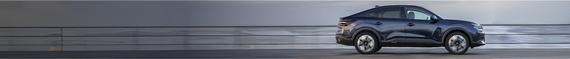 A black car on a dark grey floor with a light grey background..