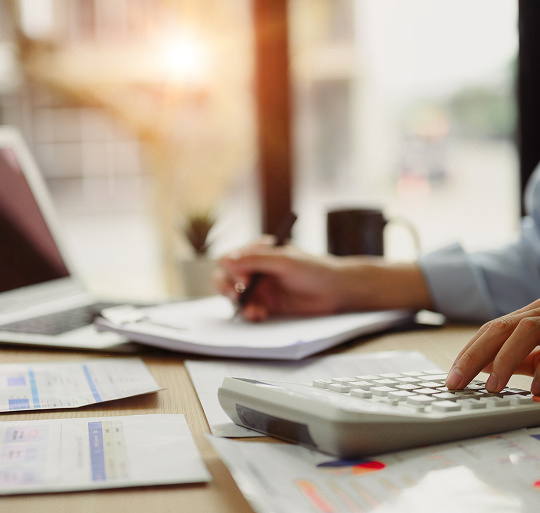 A person working with a pad of paper and a calculator in front of her.