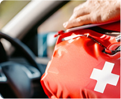A person in  a car holding a first aid or drivers kit bag.
