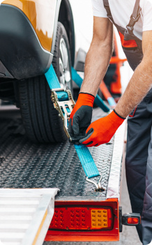 A man securing a car onto a tow truck.