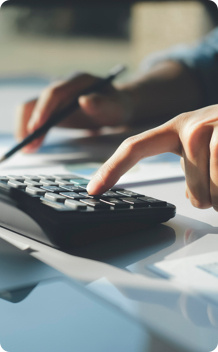 A person working on paperwork whilst using a calculator. 