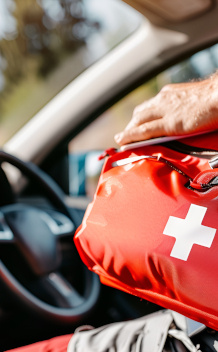 A person in  a car holding a first aid or drivers kit bag.