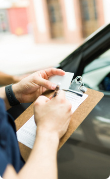 A person writing on a piece of paper on a clipboard.