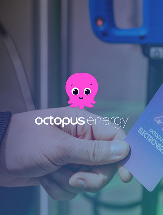 A person holding an Octopus Energy card with the Octopus Energy, pink octopus, logo sitting above the image.