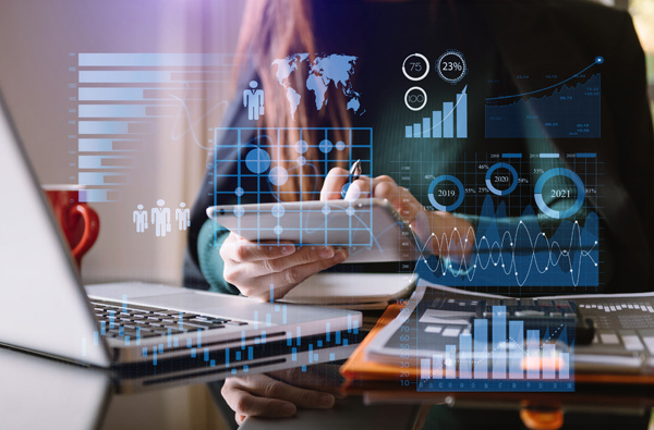A lady working on an ipad surrounded with icons representing data and reports.