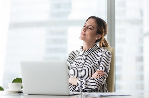 A lady sat at a laptop looking pleased.
