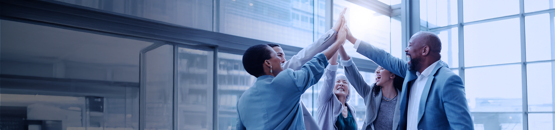 A team of office workers high fiving each other, celebrating a success.