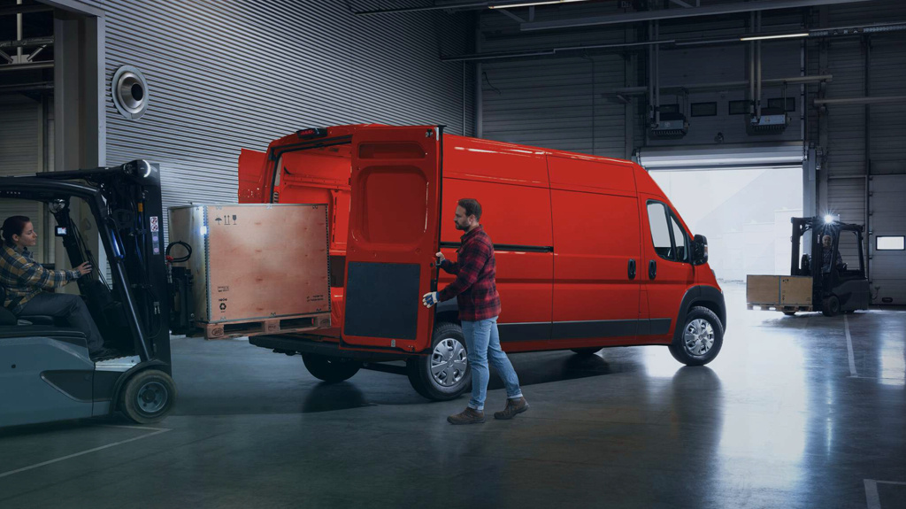 Two people packing wooden crates into a van