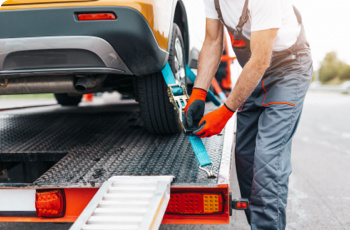 A man securing a car on a tow truck