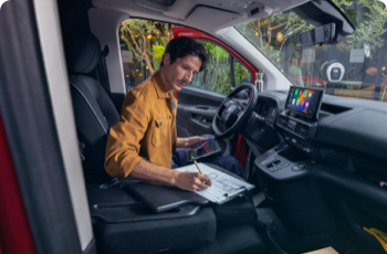 Man sat in a van writing on a notepad