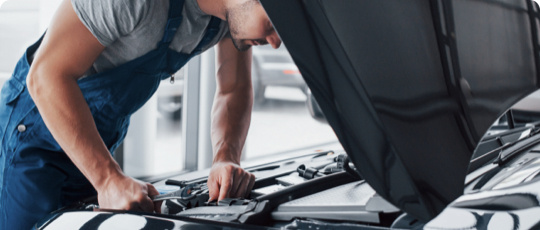 A man looking under the hood of a car.