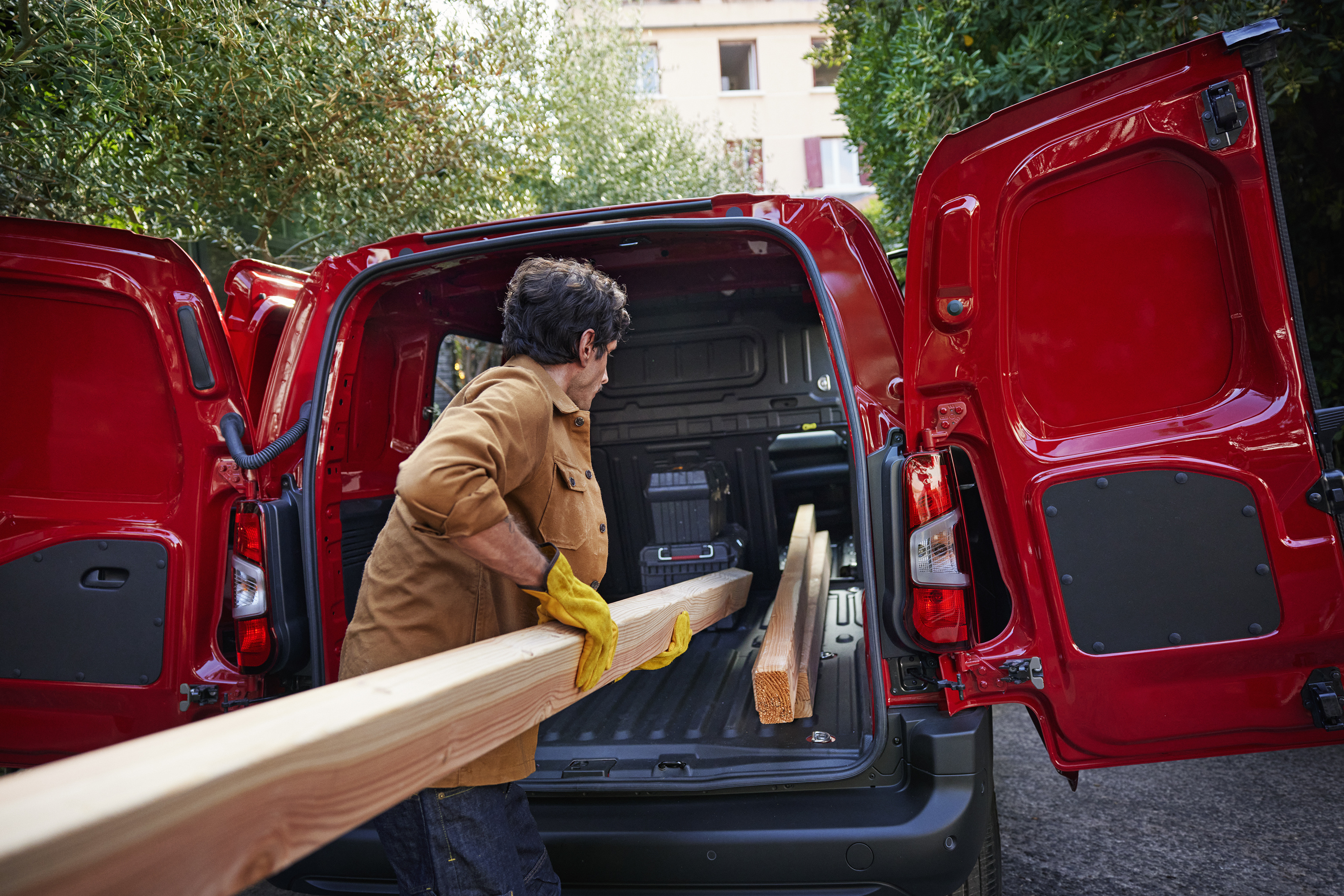A man putting planks of wood into the back of a van.
