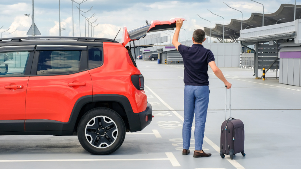 A man getting a suitcase out of an orange car. car.